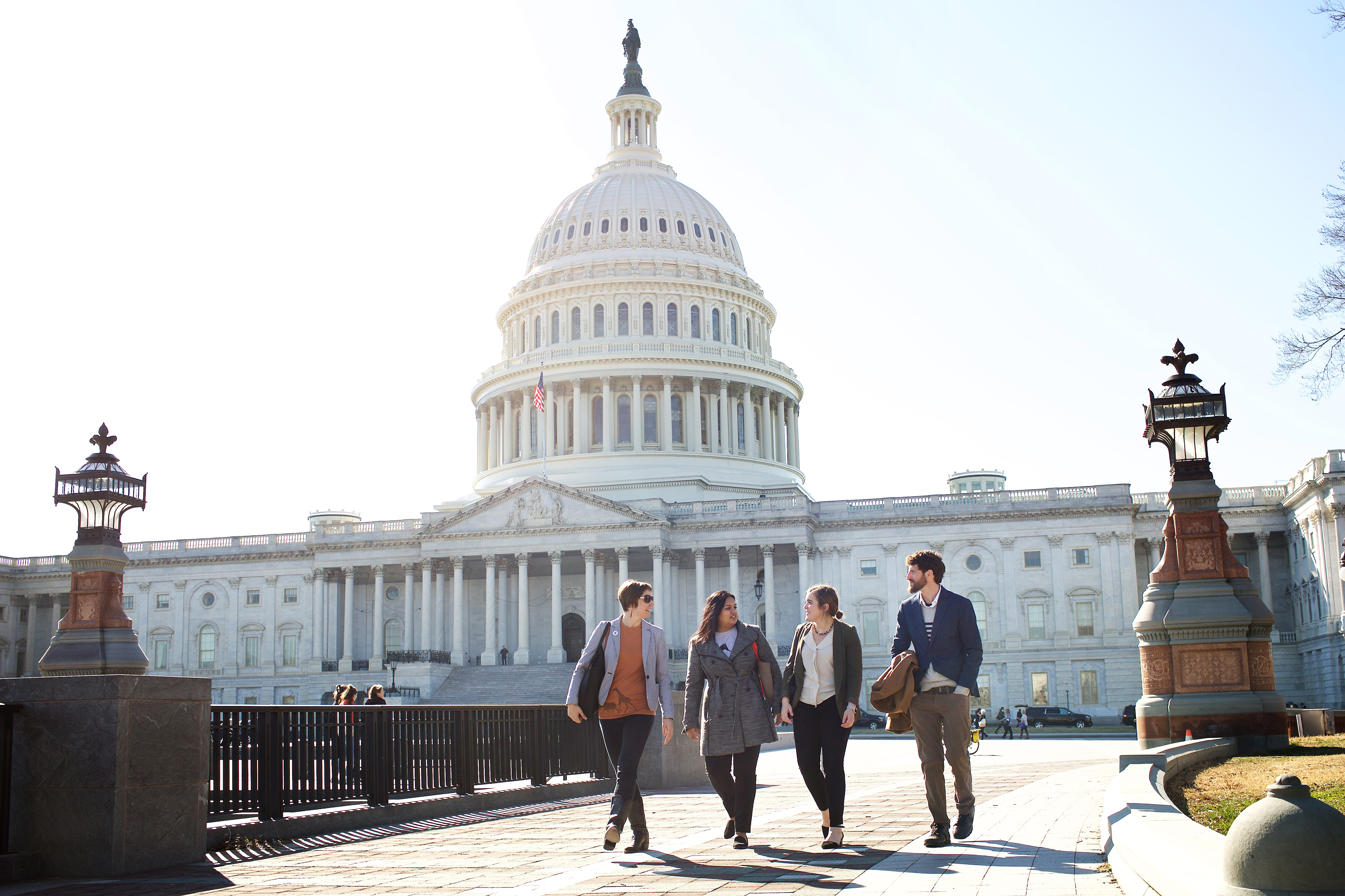 A group of people walking outside with the United States Capitol building behind them
